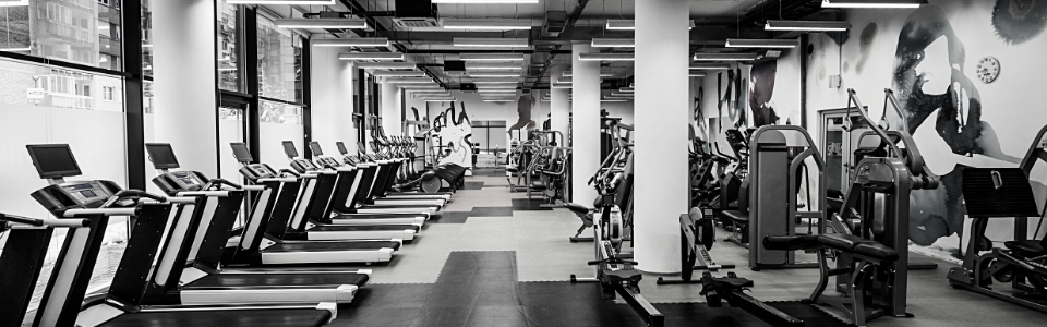 An empty gym with various exercise equipment, symbolizing the challenge of maintaining consistent workout routines.